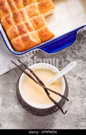 Buchteln, panini dolci a base di lievito con latte e burro, serviti con salsa alla vaniglia. Piatto tradizionale senza carne in Europa Foto Stock