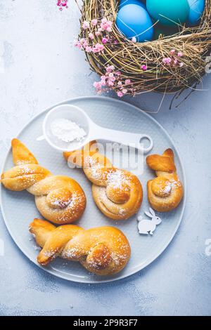 Cottura di Pasqua - conigli di pasta di lievito a forma di coniglietto pasquale e uova colorate Foto Stock