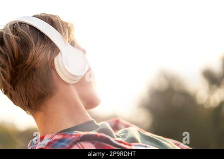 Giovane donna urbana con capelli corti in cuffie grandi primo piano. Foto Stock