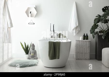 Elegante bagno interno con vasca moderna, piante e splendido decor. Design domestico Foto Stock