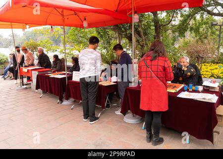 Hanoi, Vietnam. Jnauary 2023. L'uomo per strada scrive parole di buon auspicio sui segni rossi durante la vigilia di Capodanno cinese Foto Stock