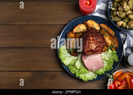 Piatto posa composizione con delizioso prosciutto e altri piatti di festa su tavolo di legno, spazio per il testo. Cena di Natale Foto Stock