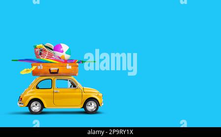 Auto giallo retro con bagagli e attrezzature da spiaggia sul tetto Foto Stock