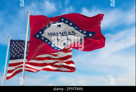 Bandiera dello stato dell'Arkansas, USA di fronte alla bandiera ufficiale degli Stati Uniti su sfondo cielo nuvoloso. Stati Uniti d'America concetto patriottico. copia spazio per verti Foto Stock
