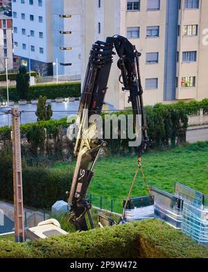 I pannelli di vetro sono consegnati al tetto piano di un blocco di appartamenti da una gru a distanza montata su autocarro al crepuscolo Santander Cantabria Spagna Foto Stock