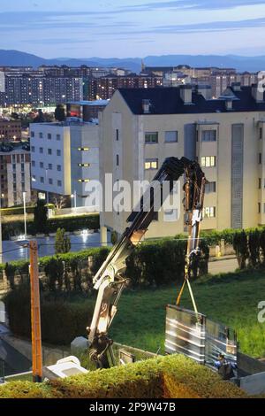 I pannelli di vetro sono consegnati al tetto piano di un blocco di appartamenti da una gru a distanza montata su autocarro al crepuscolo Santander Cantabria Spagna Foto Stock