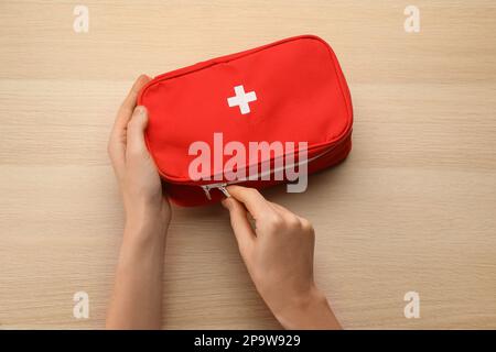 Donna apertura borsa kit di pronto soccorso su tavolo di legno chiaro, vista dall'alto Foto Stock