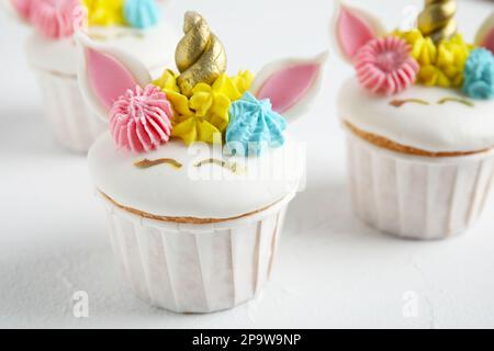 Tortini dolci e carini di unicorno su un tavolo bianco, primo piano Foto Stock