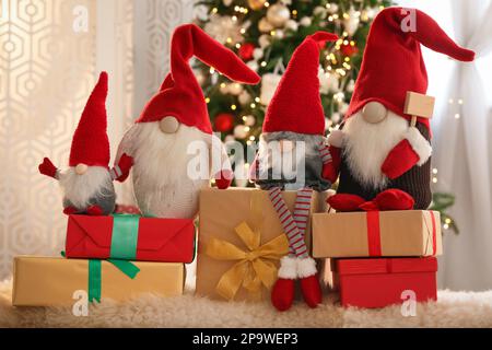 Simpatici gnomi di Natale e scatole regalo sul tappeto in camera Foto Stock