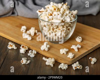 Popcorn in ciotola di vetro su sfondo di legno Foto Stock