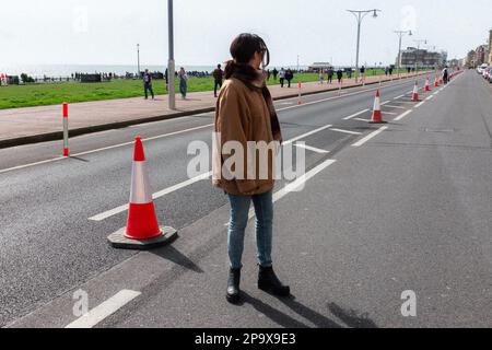 Woman si trova vicino a Kingsway per la maratona sul lungomare di Hove, Brighton & Hove, East Sussex, Regno Unito Foto Stock
