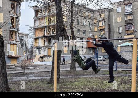 Zaporizhzhzhia, Ucraina. 25th Feb, 2023. Gli adolescenti hanno visto praticare sul bar orizzontale vicino all'edificio dell'appartamento danneggiato da una conchiglie russa. I bambini e le famiglie ucraine hanno subito un anno di violenza crescente, traumi, distruzione e sfollamenti. I bambini continuano ad essere uccisi, feriti e profondamente traumatizzati dalla violenza che ha innescato sfollamenti su una scala e velocità non viste dalla seconda guerra mondiale Credit: SOPA Images Limited/Alamy Live News Foto Stock