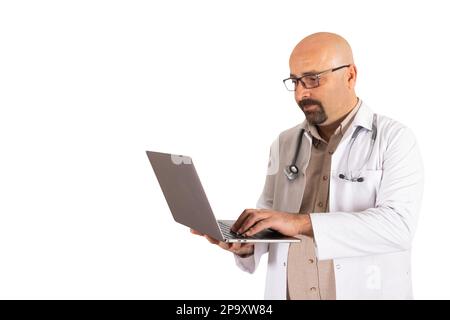 Medico che utilizza un computer portatile. Sfondo bianco isolato, spazio di copia. Medico calvo portatore di uniforme con stetoscopio, taccuino di tenuta. Scrivere, lavorare Foto Stock