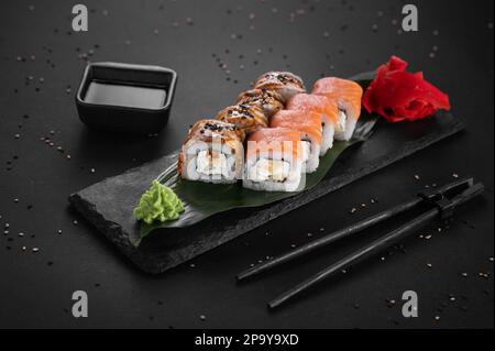 Rotolo di salmone fresco crudo, anguilla affumicata, formaggio cremoso e avocado all'interno. Foto Stock