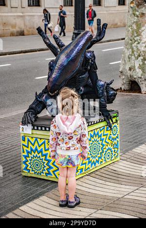 Scultura aliena nella zona della Rambla di Barcellona in corso di studio da parte di un bambino che probabilmente si sta chiedendo cosa sia sulla terra. Foto Stock