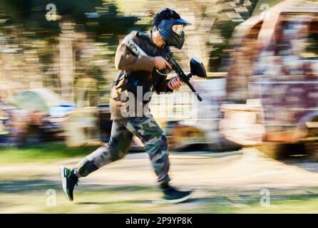 Veloce, running e paintball uomo, pistola e campo di battaglia all'aperto, parco giochi o giochi in foresta avventura formazione. Abilità di tiro, giocatore o sport Foto Stock