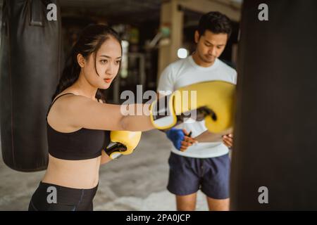 un pugile femmina in piedi punzonando la borsa pesante Foto Stock
