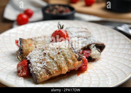 Deliziosi involtini di melanzane al forno con pomodori e formaggio su piatto, primo piano Foto Stock