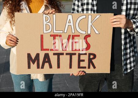 Giovane uomo e donna afroamericana che tiene il segno con la frase Black Lives Matter Outdoor, primo piano. Concetto di razzismo Foto Stock