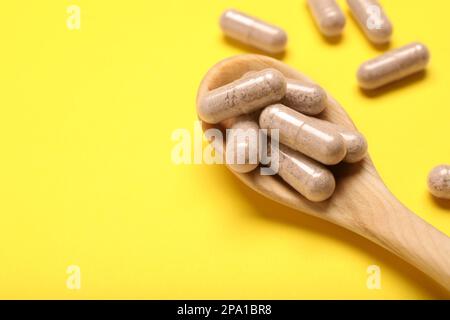 Capsule di gelatina in cucchiaio su fondo giallo, primo piano. Spazio per il testo Foto Stock