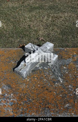 Un vecchio crocifisso in pietra e croce posati su una lapide. Foto Stock