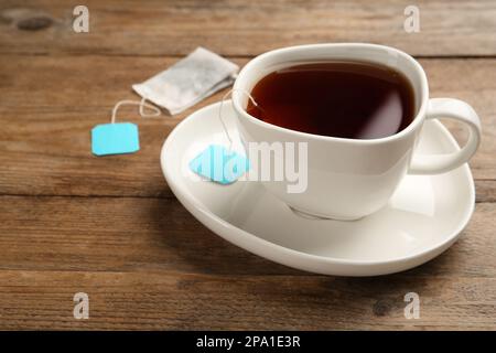 Borsa da tè in tazza di ceramica di acqua calda su tavolo di legno. Spazio per il testo Foto Stock