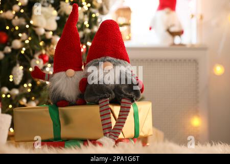 Simpatici gnomi di Natale e scatole regalo sul tappeto in camera Foto Stock