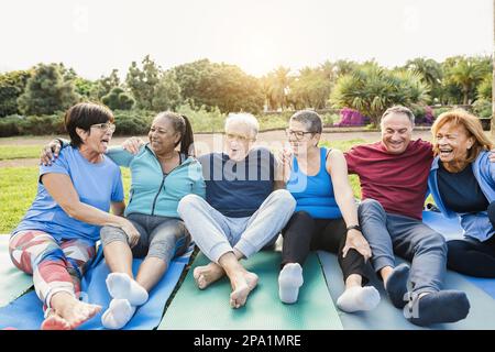 Persone anziane multirazziali divertirsi dopo l'allenamento esercizi all'aperto con parco cittadino in background - stile di vita sano e gioioso stile di vita anziano con Foto Stock