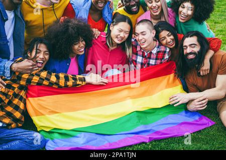 Persone diverse che hanno divertimento tenendo la bandiera arcobaleno LGBT all'aperto - Focus sul volto della ragazza calva Foto Stock