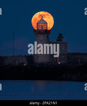 L'intera Luna di Worm che sorge dietro il faro di Howth Foto Stock