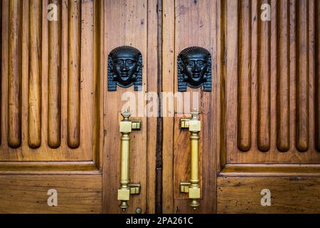 Dettaglio di due di bronzo Sphinx teste su una vecchia porta di legno - circa un centinaio di anni, palazzo italiano in nord Italia Foto Stock