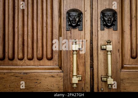 Dettaglio di due di bronzo Sphinx teste su una vecchia porta di legno - circa un centinaio di anni, palazzo italiano in nord Italia Foto Stock