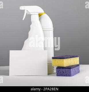 Concetto di pulizia con mockup di carte di carta e detergenti chimici in bottiglie di plastica e spugne di lavaggio Foto Stock