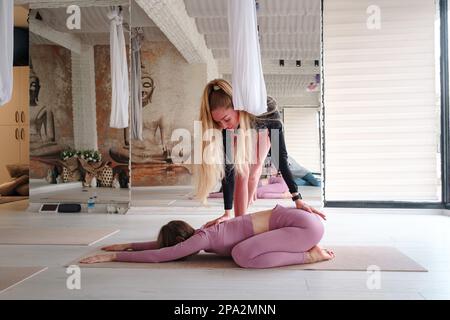 laboratorio di yoga d'aria e stretching in studio yoga. Bella donna che pratica yoga aereo con personal trainer in studio Foto Stock