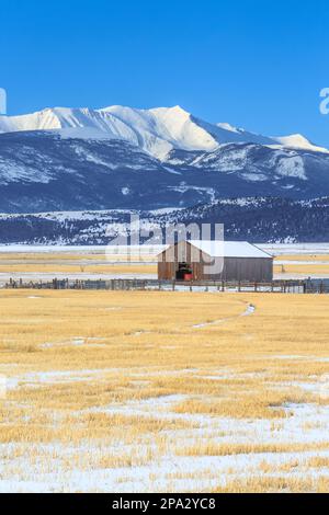 fienile e campi di fattoria sotto il monte haggin in inverno nei pressi di anaconda, montana Foto Stock