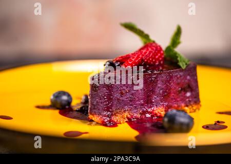 primo piano di mousse di frutti di bosco con fragole su un piatto giallo. Foto Stock