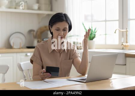 Preoccupata donna di casa matura che conta le spese sulla calcolatrice Foto Stock