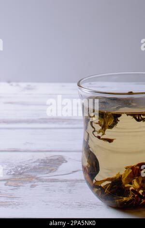 tazza con tè verde e teiera sullo sfondo di un tavolo di legno bianco. bello sopra la luce Foto Stock