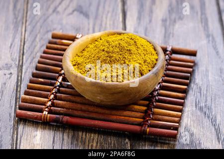 Il curry in polvere viene preparato mescolando le spezie in una ciotola di legno sul tavolo Foto Stock