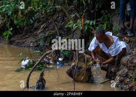 Un devoto osun beve acqua dal fiume Osun durante l'annuale Osun Osombo Festival a Osun, Nigeria. Foto Stock