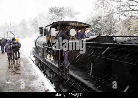 Locomotiva a vapore 52044 Classe 25 Ironclad che ha recitato nel film Railway Children tira nella stazione di Oxenhope durante una tempesta di neve Foto Stock