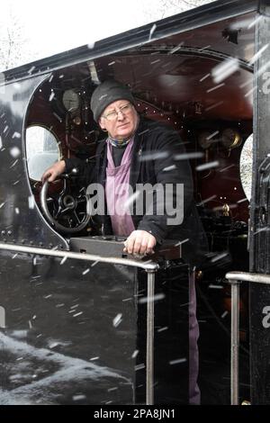 Steam Engine driver shunting locomotiva LNWR carbone serbatoio 1054 in una neve blizzard sulla Keighley e Worth Valley Railway Foto Stock