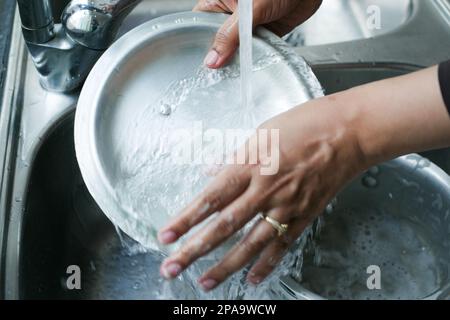 Donna casalinga che lava una pentola Foto Stock