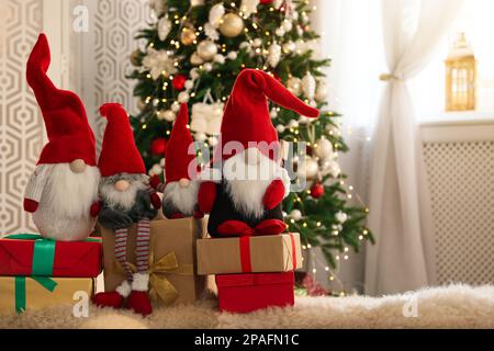 Simpatici gnomi di Natale e scatole regalo sul tappeto in camera Foto Stock