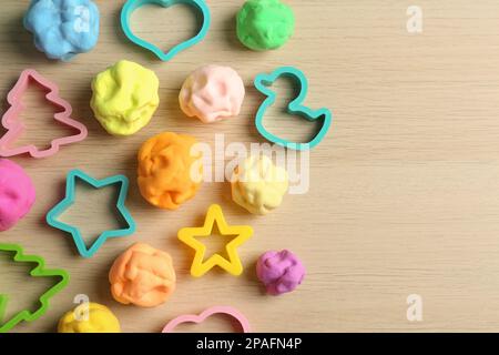 Pasta di colore diverso gioco con stampi su tavolo di legno, piatto. Spazio per il testo Foto Stock