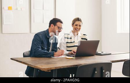 Uomini d'affari felici sorridenti allegri durante una riunione online con i loro clienti globali. Due giovani uomini d'affari che hanno una videoconferenza in una cr Foto Stock