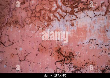La struttura di un antico muro rustico è ricoperta di stucco rosa Foto Stock
