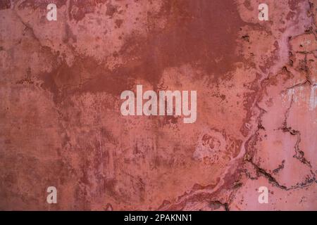 La struttura di un antico muro rustico è ricoperta di stucco rosa Foto Stock