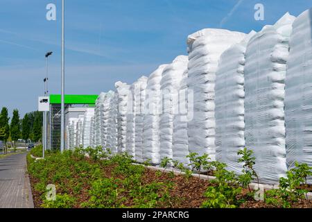 Mucchio di sacchi di plastica bianchi accatastati lungo il marciapiede. Cielo blu con nuvole di luce. Foto Stock