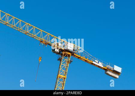 Frammento di una gru gialla con cabina contro il cielo blu Foto Stock